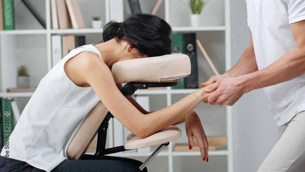 cropped view of masseur making hands massage to businesswoman on massage chair cropped view of masseur making hands massage to businesswoman on massage chair