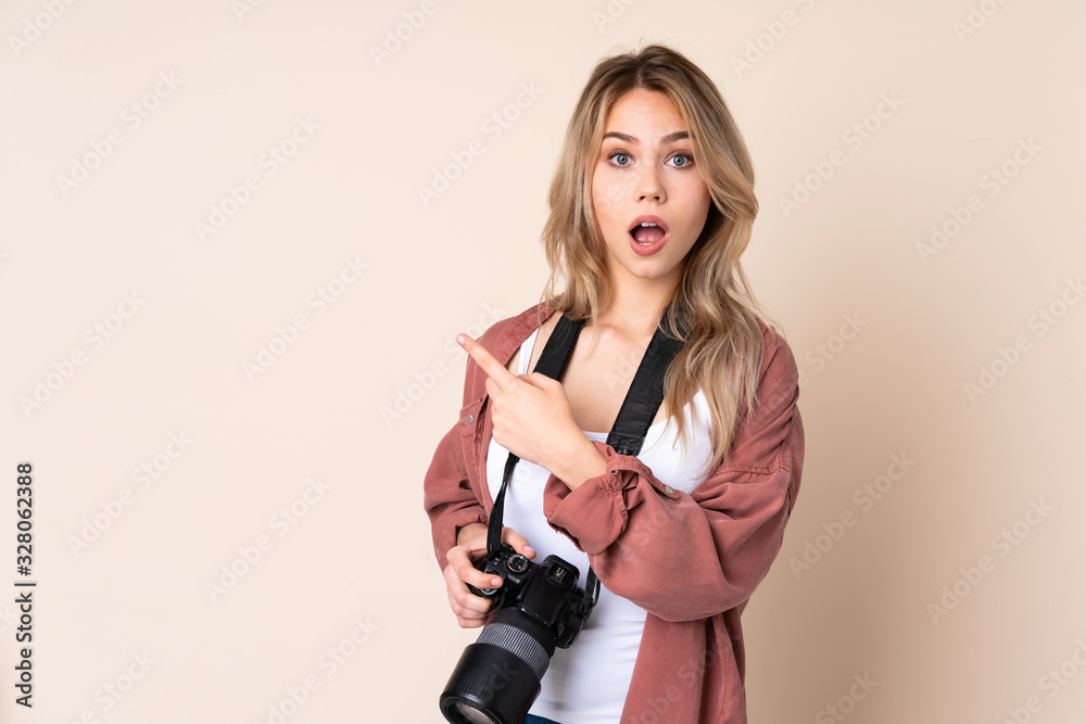 Young photographer girl over isolated background surprised and pointing side Young photographer girl over isolated background surprised and pointing side