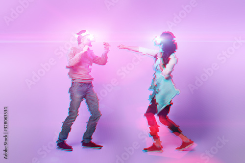 Couple with virtual reality headset are playing game and fighting. Image with glitch effect.