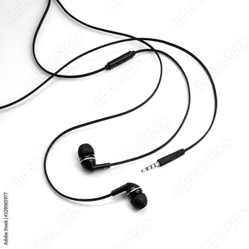 Wired earplugs for listening music and sounds on portable devices isolated on white background. Black audio headphones headset. In-ear vacuum earphones for music lovers.