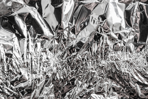 Texture of used crumpled aluminium food foil background. Shiny aluminum foil wrap without chocolate candy.