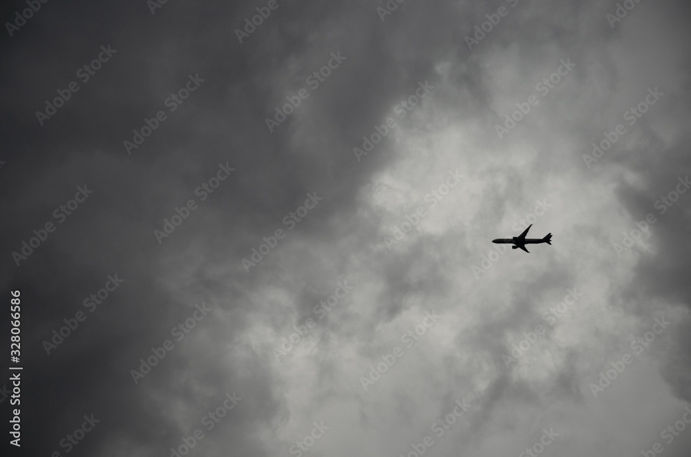 Airplane flying through dark stormy clouds in dramatic sky Airplane flying through dark stormy clouds in dramatic sky