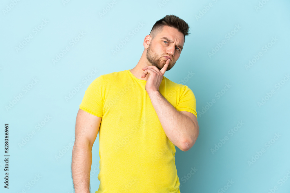 Russian handsome man isolated on blue background having doubts while looking up Russian handsome man isolated on blue background having doubts while looking up