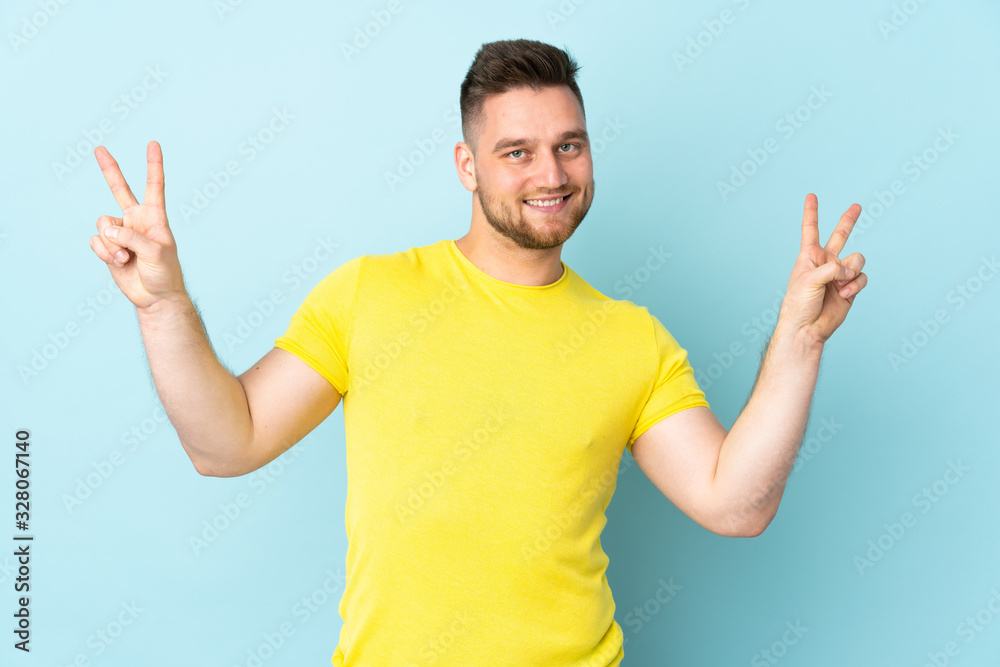 Russian handsome man isolated on blue background showing victory sign with both hands Russian handsome man isolated on blue background showing victory sign with both hands