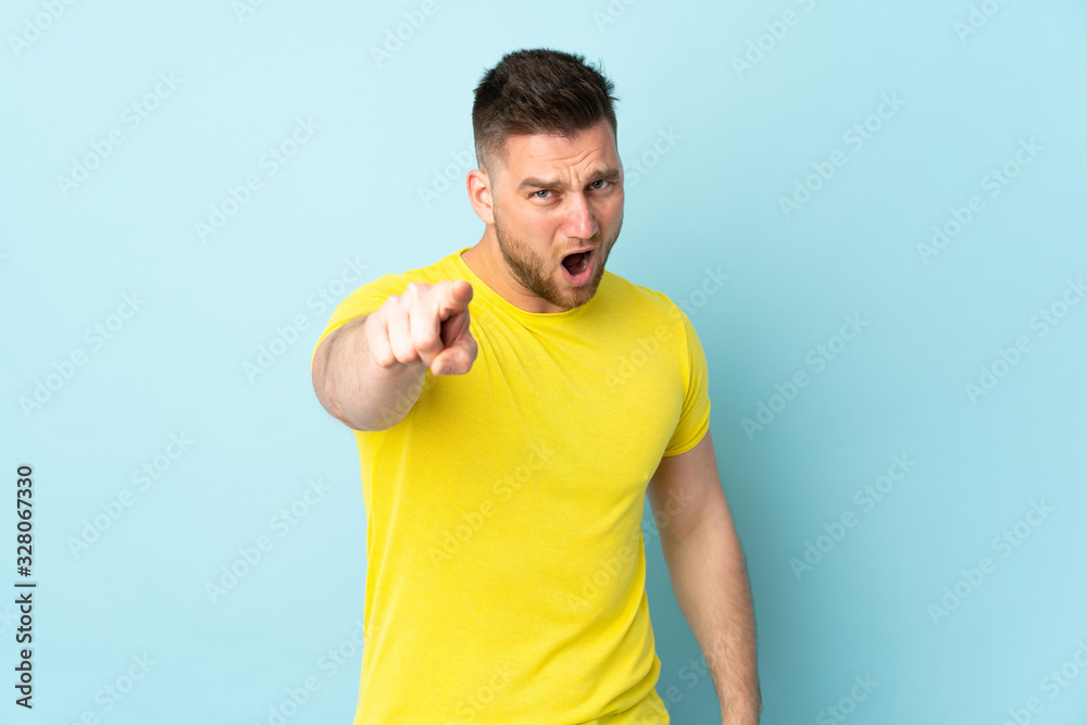Russian handsome man isolated on blue background frustrated and pointing to the front Russian handsome man isolated on blue background frustrated and pointing to the front