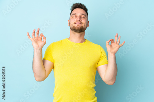 Russian handsome man isolated on blue background in zen pose