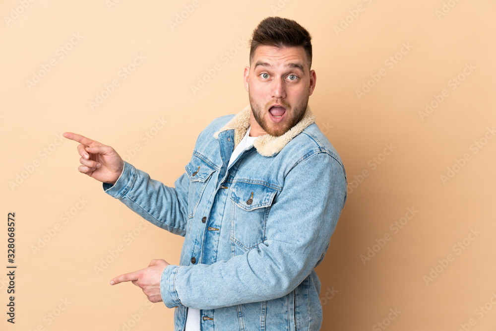 Russian handsome man over isolated background surprised and pointing side