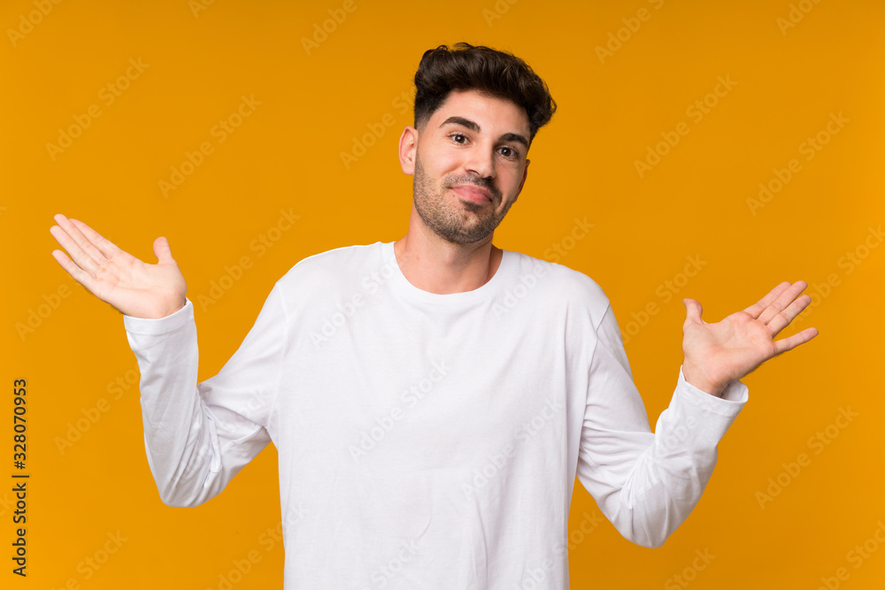 Young man over isolated orange background having doubts while raising hands Young man over isolated orange background having doubts while raising hands