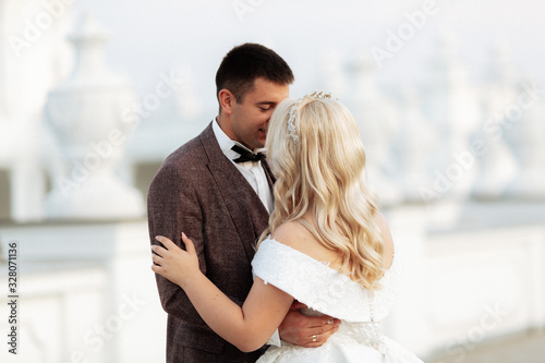 The bride and groom walk together in the park. Charming bride in a white dress, the groom is dressed in a dark elegant suit © ostap_davydiak