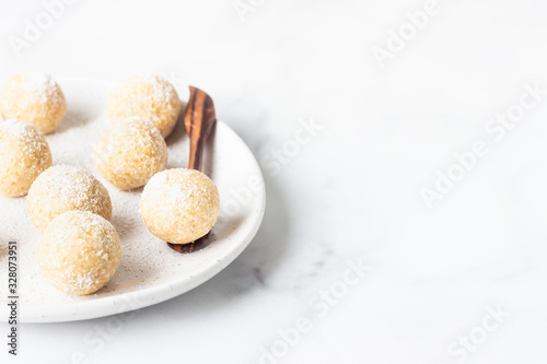 Traditional Indian festival sweets (Laddoo or Laddu) with coconut flakes on a ceramic plate, light background, selective focus. Popular tea time sweet snack in India.
