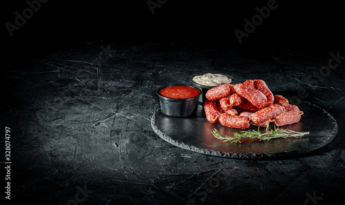 Pile of tasty delicious smoked dried sausages, salami or kabanos is on dark background photo