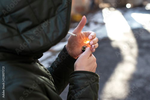 woman in a hood cigarette lighter street. hands close-up