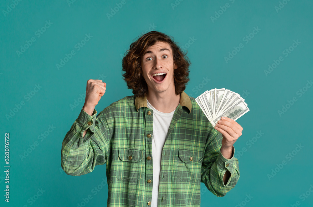 Winning lottery concept. Happy young man with money on turquoise background Winning lottery concept. Happy young man with money on turquoise background