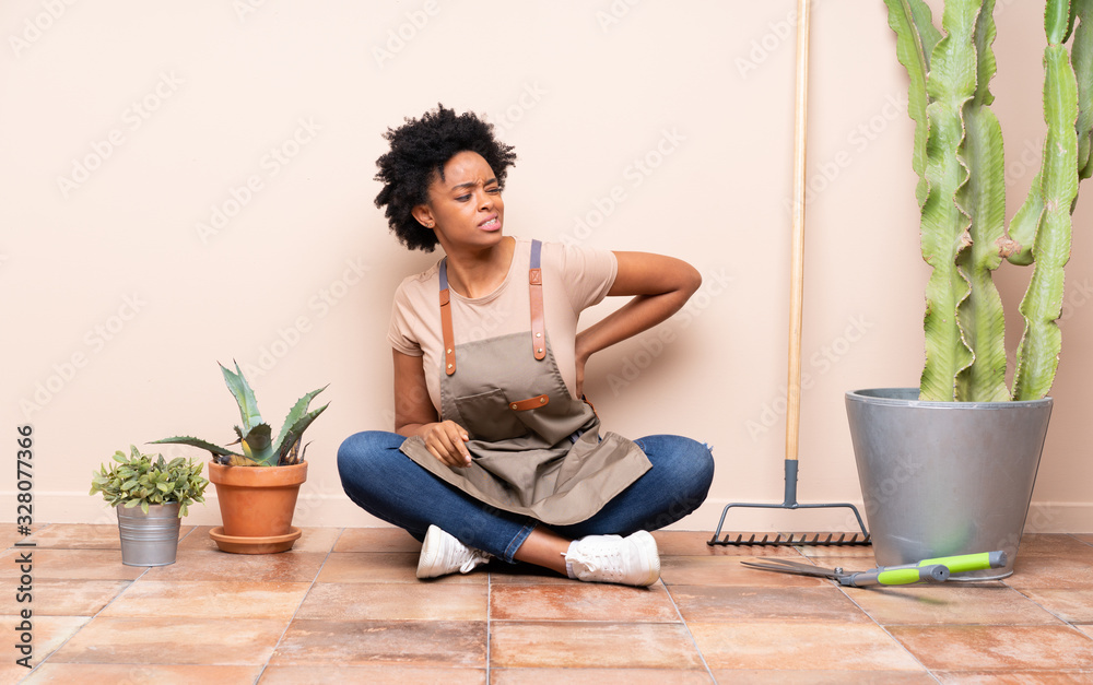 Gardener woman sitting on the floor suffering from backache for having made an effort