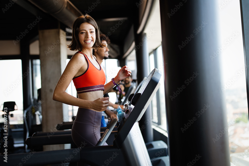 Young people running on a treadmill in modern gym Young people running on a treadmill in modern gym