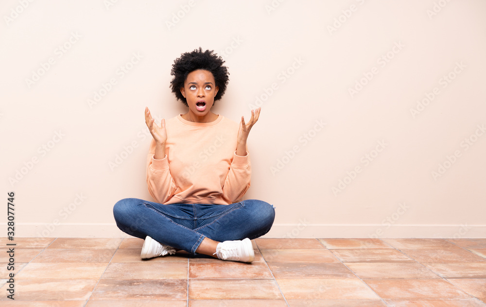 African american woman sitting on the floor frustrated by a bad situation