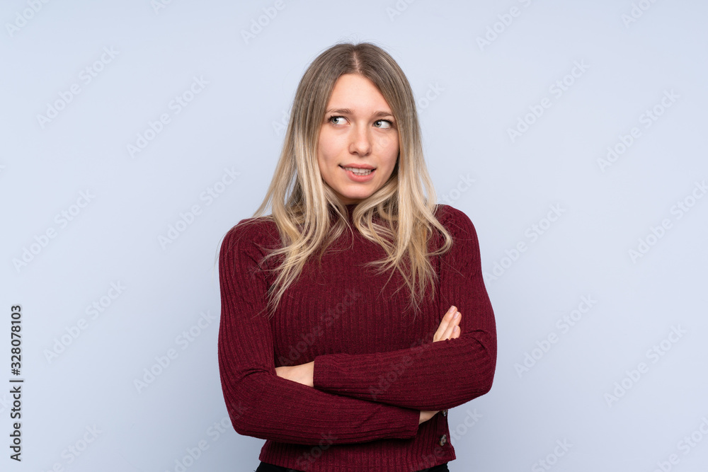 Young blonde woman over isolated blue background with confuse face expression Young blonde woman over isolated blue background with confuse face expression