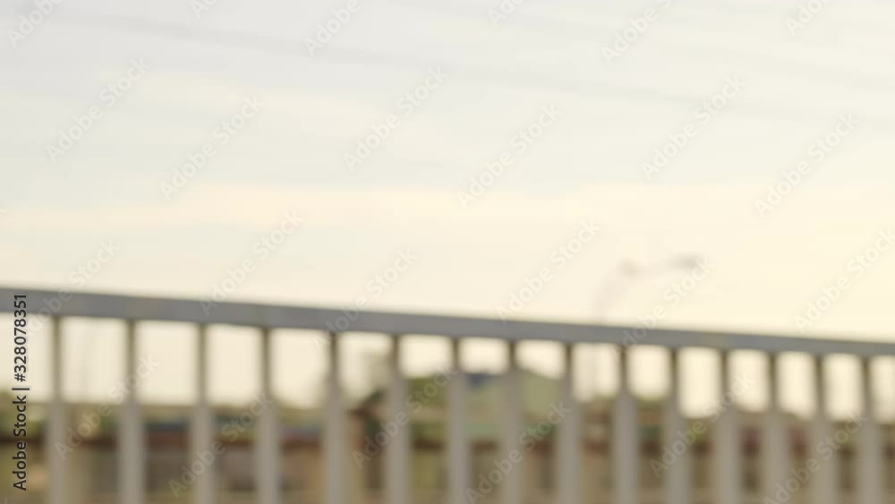 A slim focused young woman in an orange hoodie is run outdoors on the bridge in the early morning A slim focused young woman in an orange hoodie is run outdoors on the bridge in the early morning