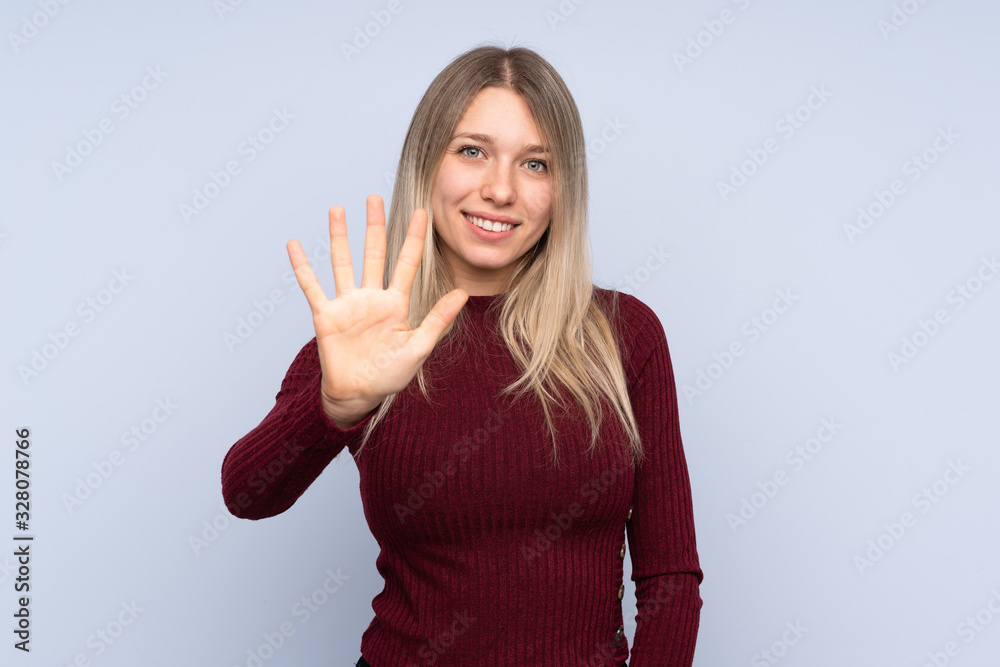 Young blonde woman over isolated blue background counting five with fingers Young blonde woman over isolated blue background counting five with fingers