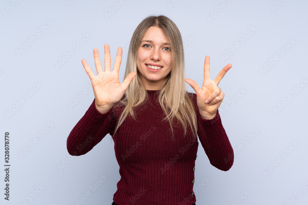 Young blonde woman over isolated blue background counting eight with fingers