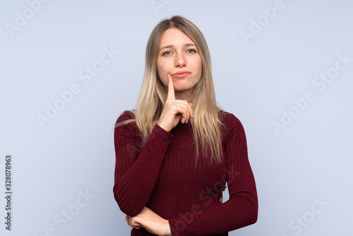 Young blonde woman over isolated blue background Looking front