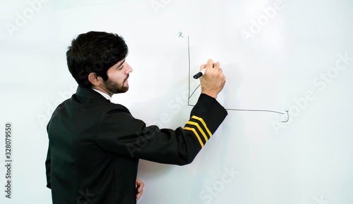 Young pilot man in uniform writing graph by marker on whiteboard having discussion with business man about aviation businessn,startup,business team,people,economics,analytics and statistics concept, photo