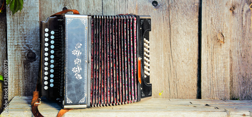 Fotografie Old lonely accordion on the bench in summer sunny weather