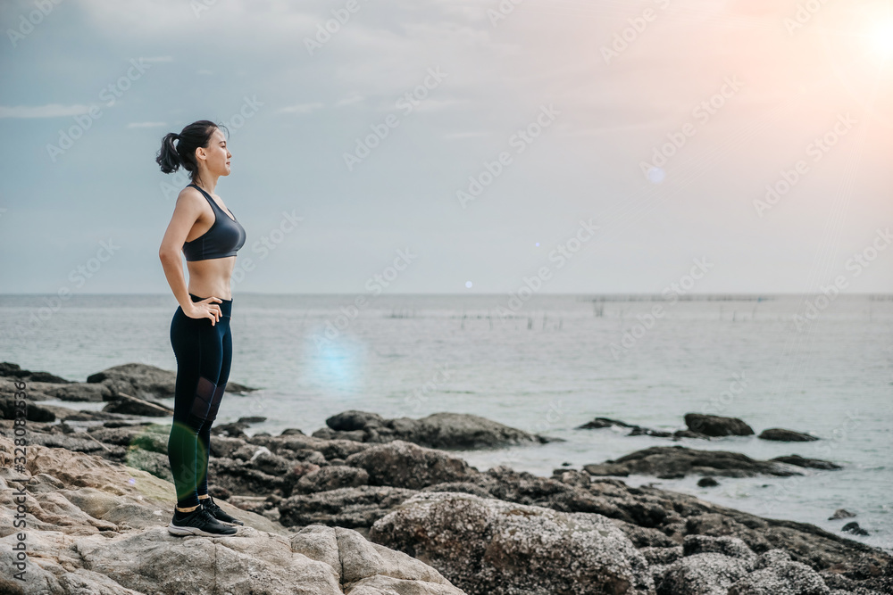 Sporty young Asian woman get tired after running on sidewalk in morning. Health conscious concept with copy space.