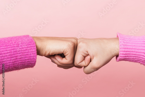 Photos Image of two girls bumping their fists together in conciliation