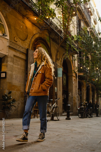 Photography Blond girl walking through the streets of the center of the city of Barcelona in Catalonia, Spain wearing a jacket and blue jeans