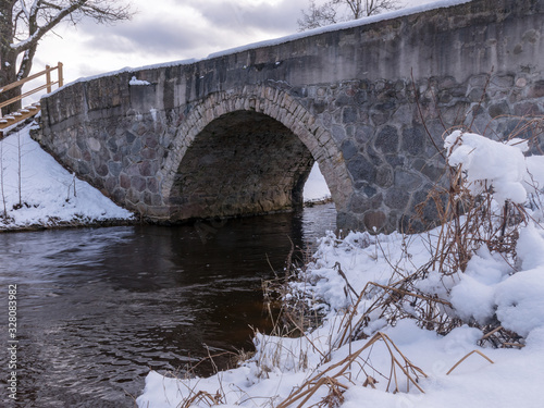 arched bridge over a fast flowing river © ANDA