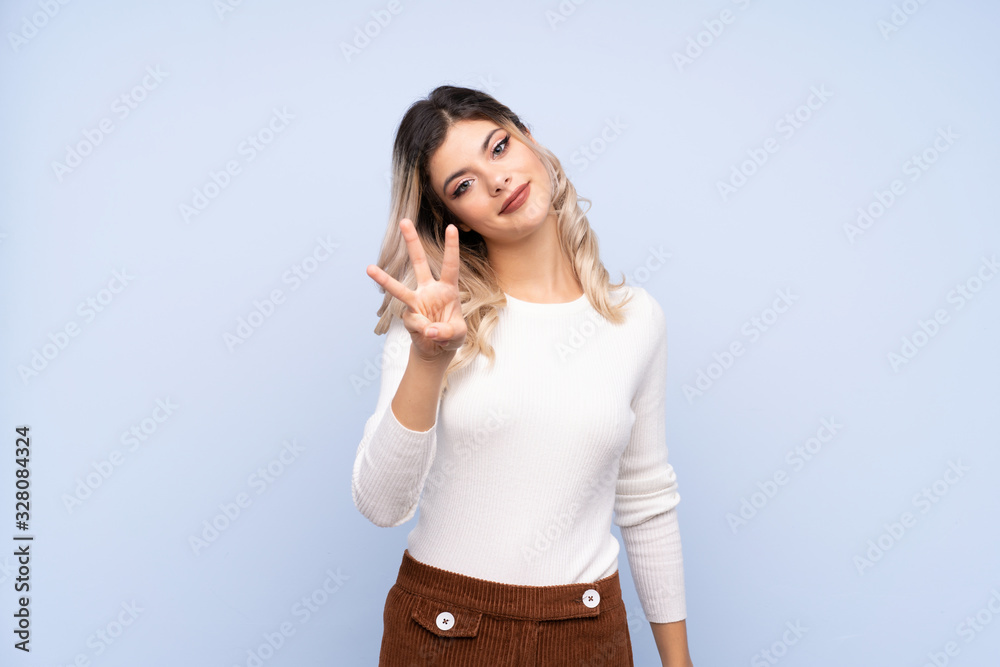 Young teenager girl over isolated blue background happy and counting three with fingers Young teenager girl over isolated blue background happy and counting three with fingers