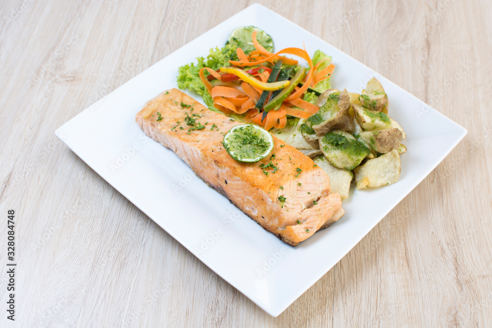 Salmon with garlic and lemon, accompanied by sauteed vegetables and spicy potatoes