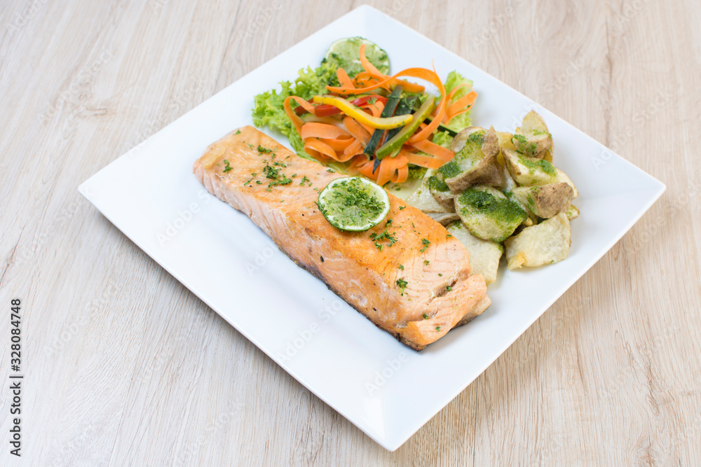 Salmon with garlic and lemon, accompanied by sauteed vegetables and spicy potatoes Salmon with garlic and lemon, accompanied by sauteed vegetables and spicy potatoes