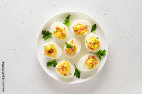 Deviled stuffed eggs with egg yolk, bacon, mustard and parsley