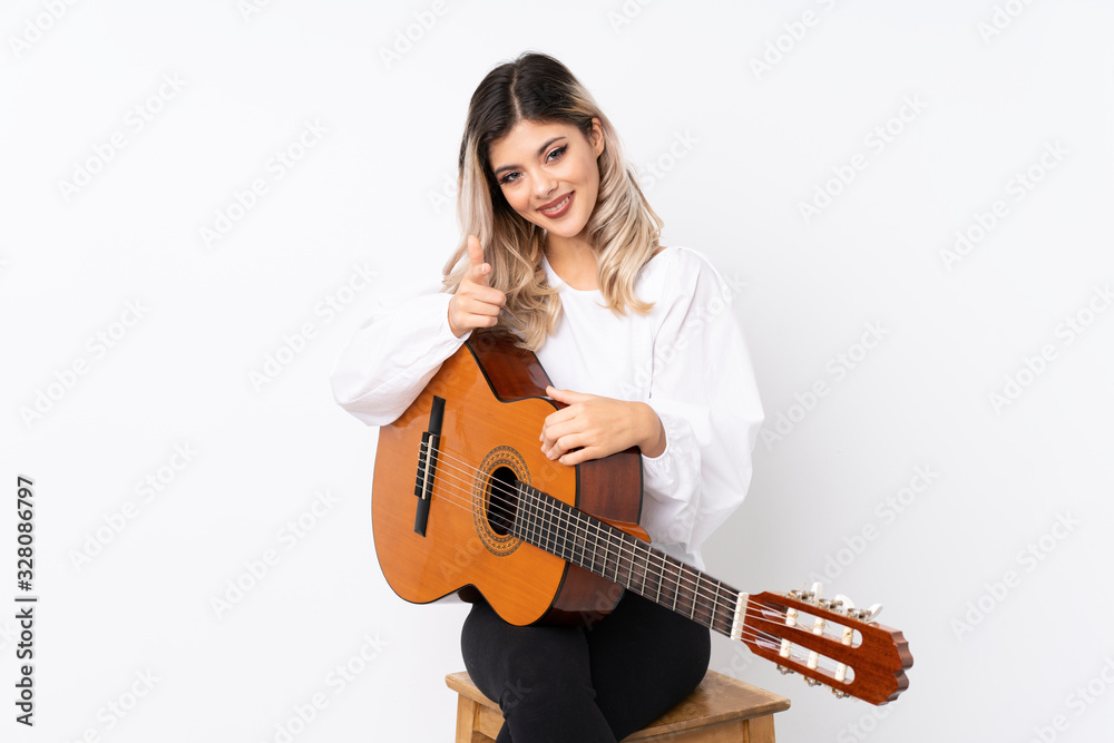 Teenager girl with guitar over isolated white background points finger at you with a confident expression Teenager girl with guitar over isolated white background points finger at you with a confident expression