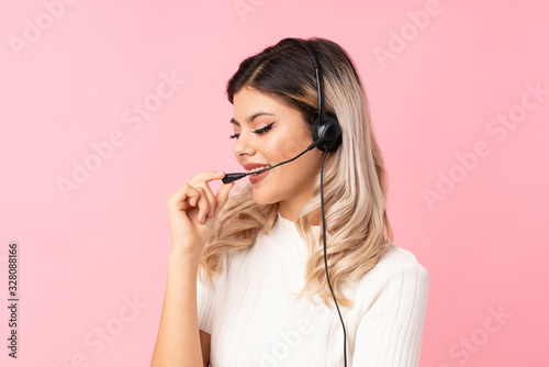 Teenager girl over isolated pink background working with headset