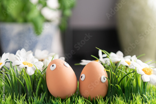 Happy Easter eggs in the kitchen among the spring grass with flowers, Easter egg hunt, egg characters with funny faces, Happy Easter concept, kitchen in the background, Easter theme, background, postc photo