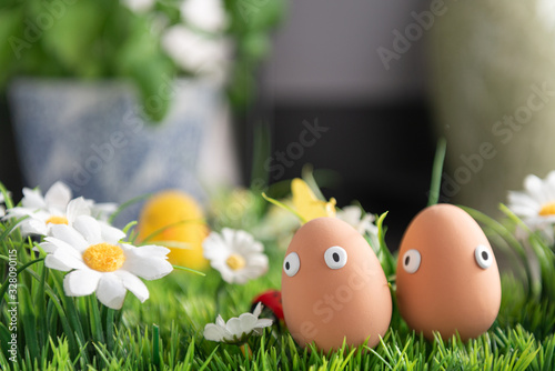 Happy Easter eggs in the kitchen among the spring grass with flowers, Easter egg hunt, egg characters with funny faces, Happy Easter concept, kitchen in the background, Easter theme, background, postc photo