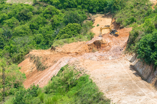 Working excavator on a mountainside in tropical jungle
