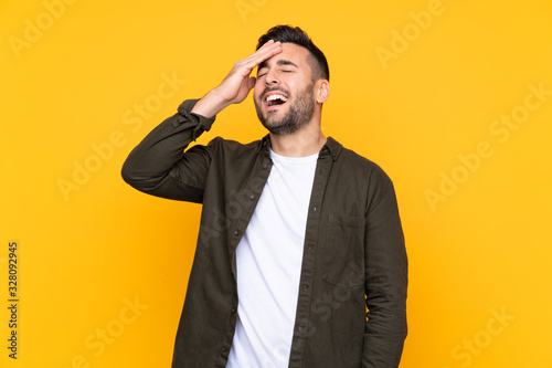 Man over isolated yellow background laughing