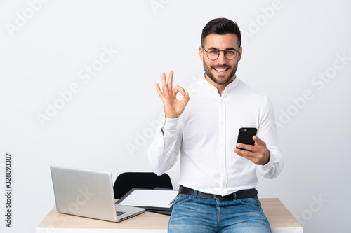 Young businessman holding a mobile phone showing an ok sign with fingers