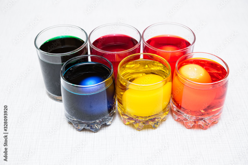 Painting process of Easter eggs by dye in the glasses. Home decorations for the holiday. Painting process of Easter eggs by dye in the glasses. Home decorations for the holiday.