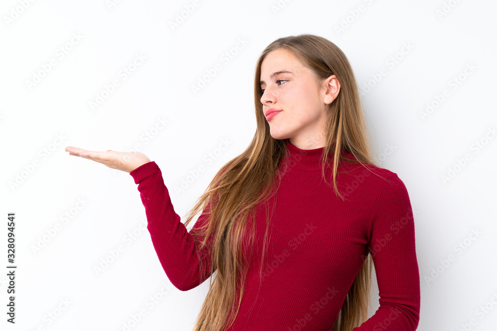 Teenager blonde girl over isolated white background holding copyspace with doubts Teenager blonde girl over isolated white background holding copyspace with doubts