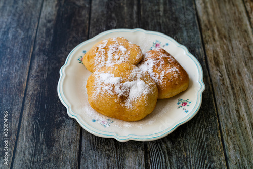 Mandazi is a slightly sweet East African Street Food; spicy, airy yeast doughnut dough made with coconut milk, flavored with cardamom and grated fresh coconut. photo