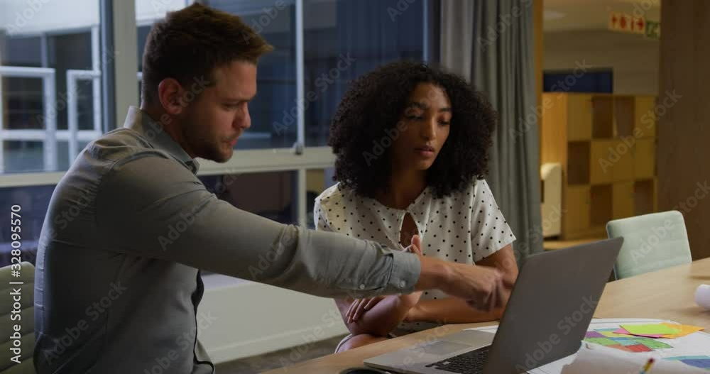 Young office executives discussing over laptop in a modern office Young office executives discussing over laptop in a modern office