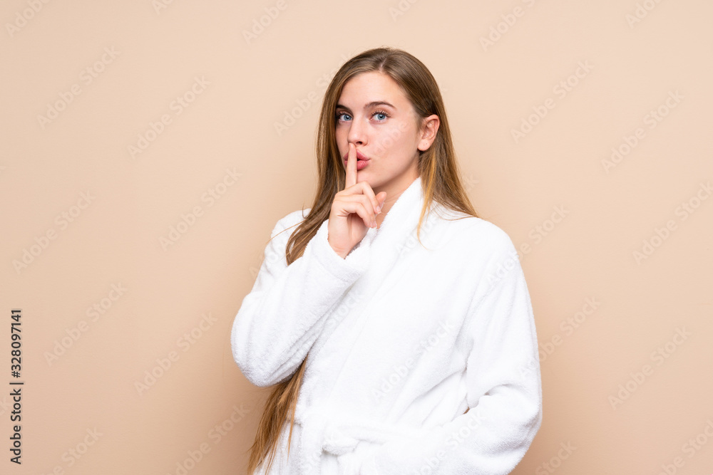 Teenager girl in a bathrobe over isolated background doing silence gesture Teenager girl in a bathrobe over isolated background doing silence gesture