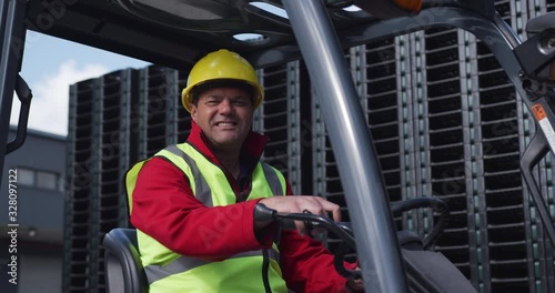 Warehouse worker driving forklift outside factory photo