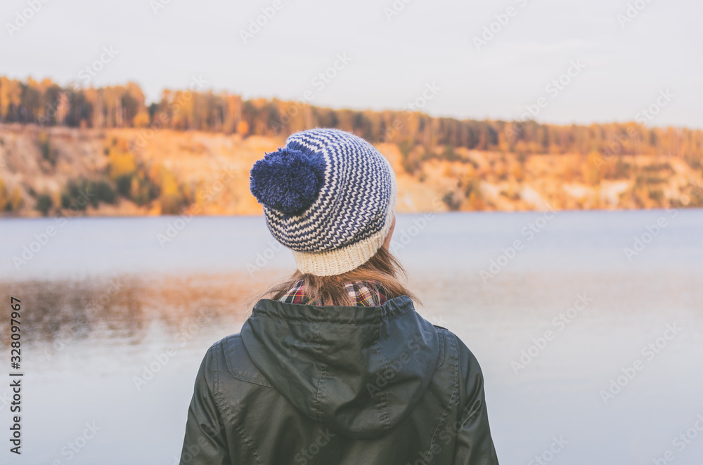 Woman in a knitted woolen hat looks at the lake Woman in a knitted woolen hat looks at the lake