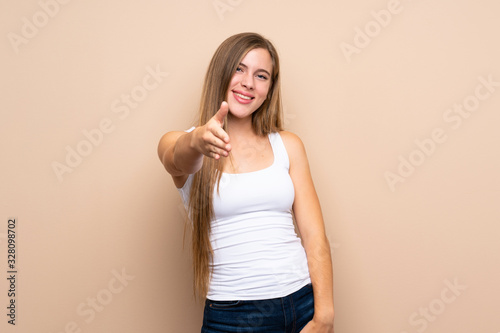 Teenager blonde girl over isolated background shaking hands for closing a good deal